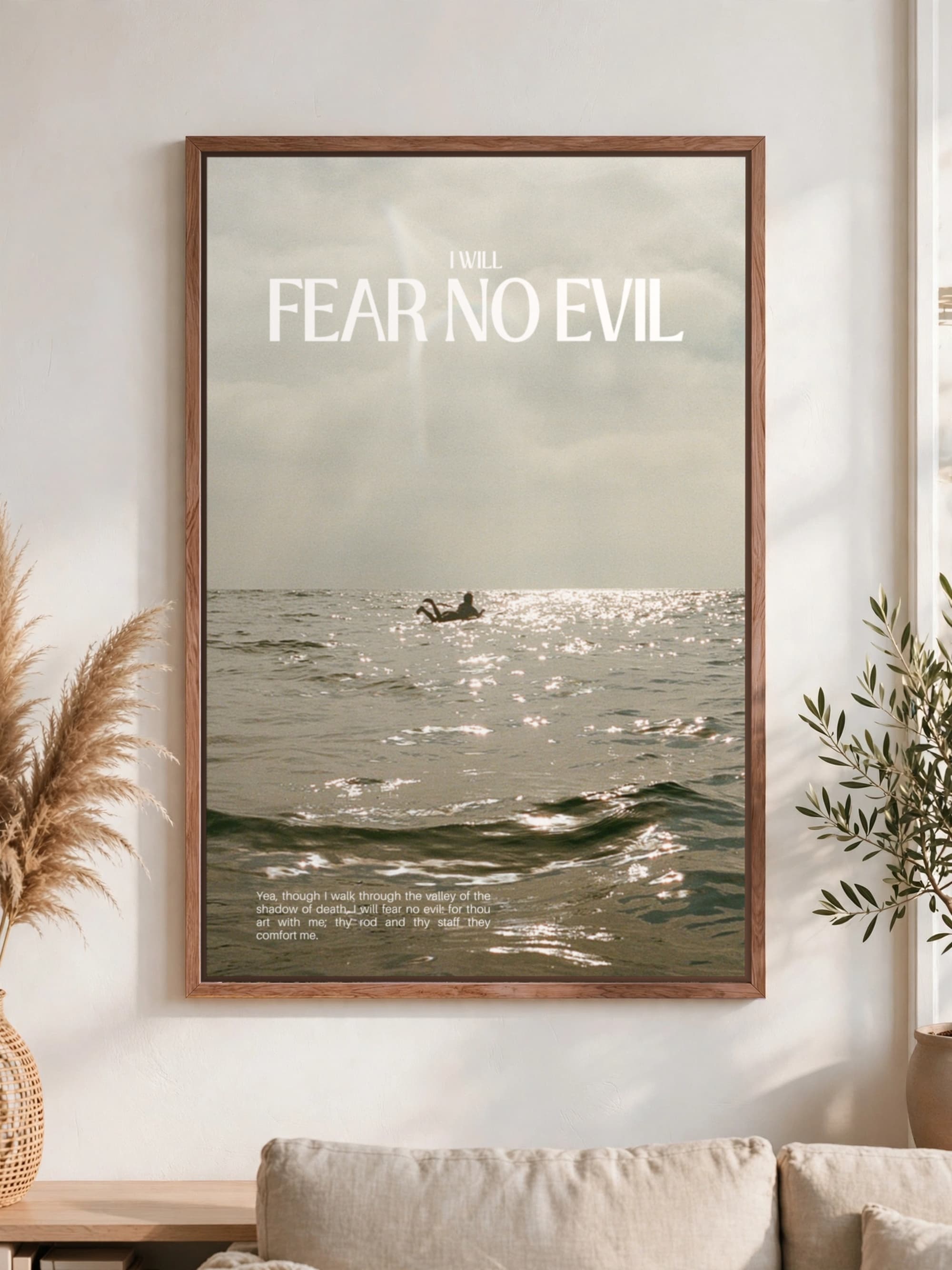 “I will fear no evil” in bold capitals over a black and white sea, pecan frame, hung above a linen sofa.